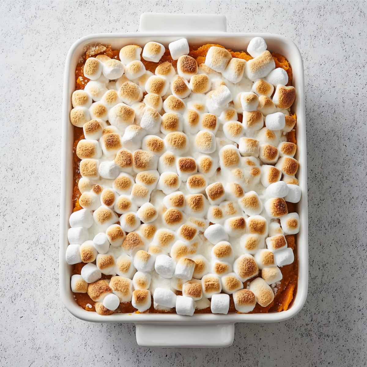 Baked sweet potato casserole topped with golden toasted mini marshmallows in a white baking dish