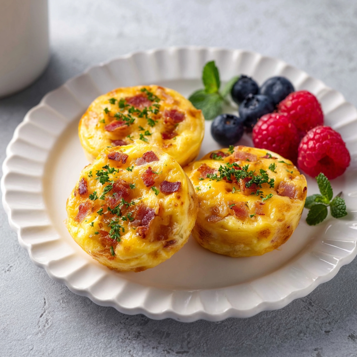 Better than Starbucks egg bites recipe cheese, served on a white plate with fresh berries.