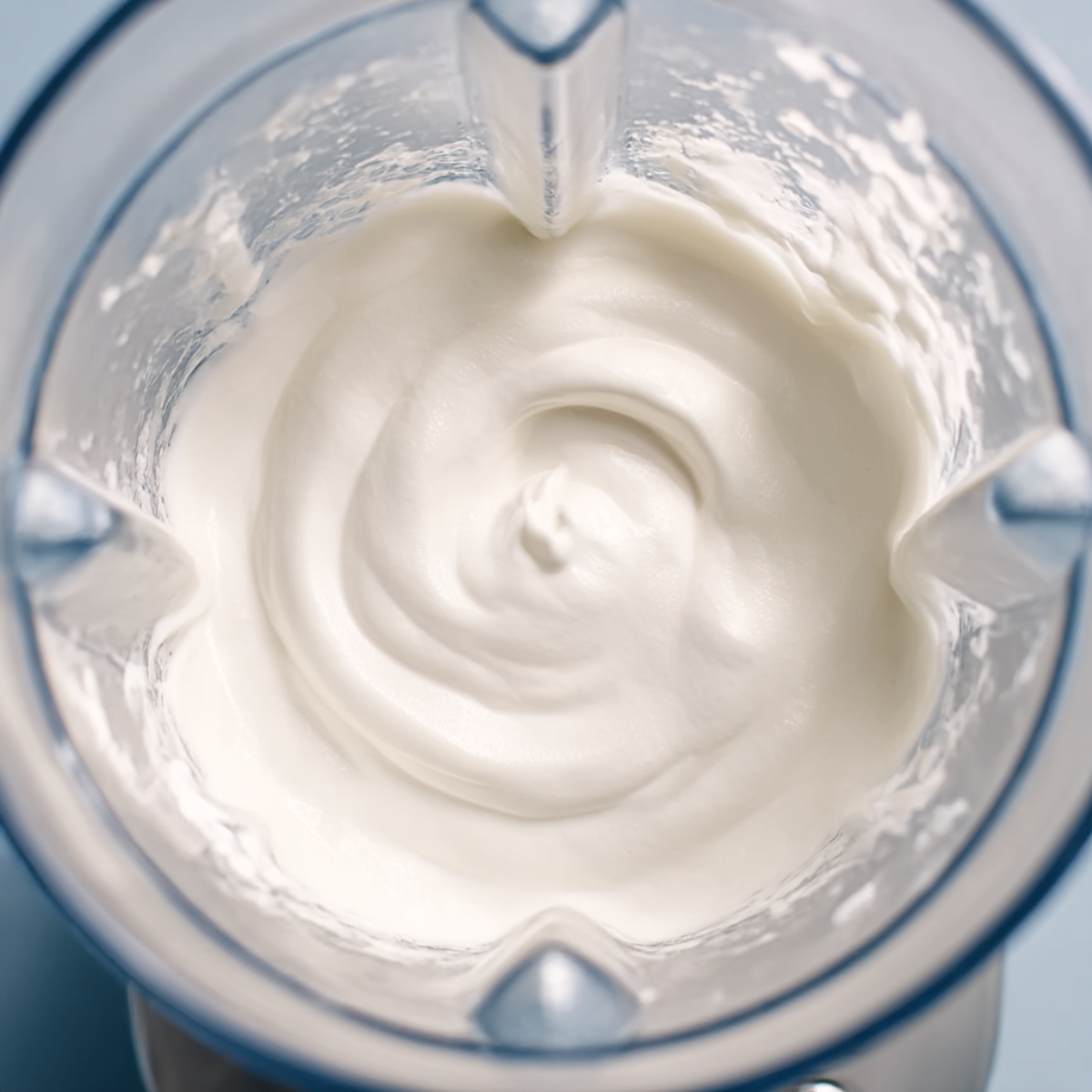 A close-up of thick whipped cream in a blender, ready to top a Christmas Mojito, enhancing its creamy, festive texture for a refreshing holiday cocktail