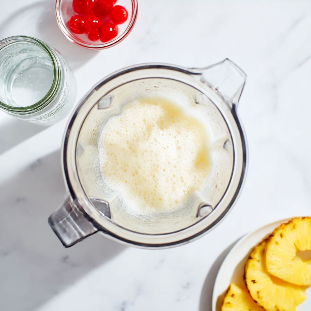 Pina colada punch blended in a glass pitcher with pineapple juice and coconut cream, easy tropical party drink recipe