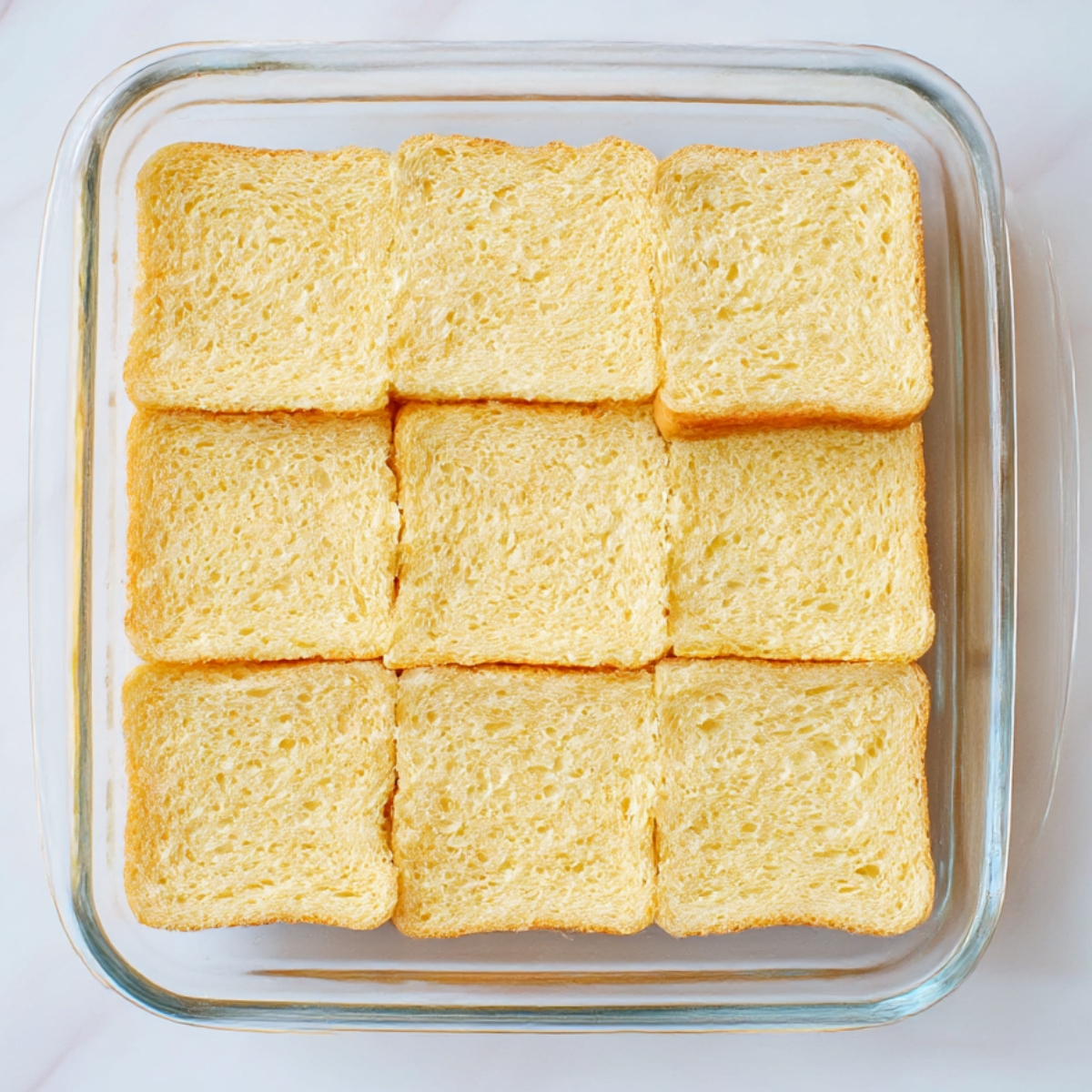 A baking dish filled with neatly arranged bread slices, ready to be transformed into breakfast sliders. Ideal for meal prep or a quick breakfast recipe