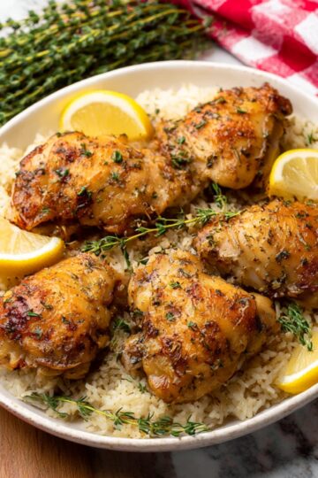 Succulent baked chicken thighs with crispy skin, seasoned with fresh thyme and lemon, served on a bed of fluffy rice. A fragrant and flavorful chicken and rice dish that is perfect for a cozy dinner.