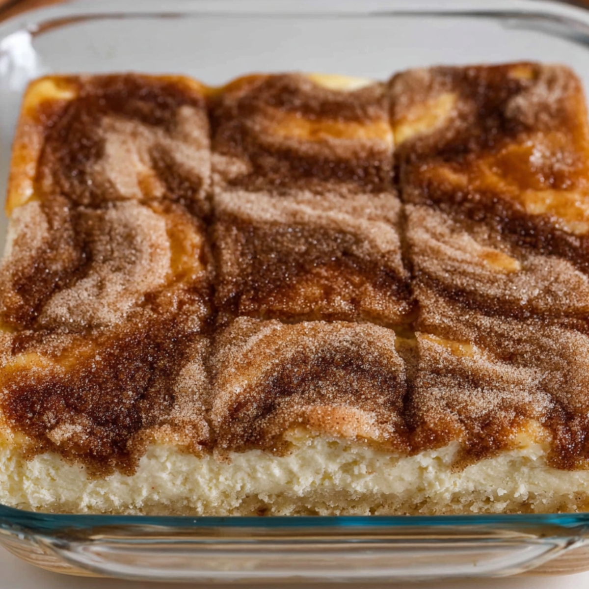 Churro cheesecake bars baked in a glass dish with creamy cheesecake filling and cinnamon sugar topping, easy homemade churro cheesecake recipe