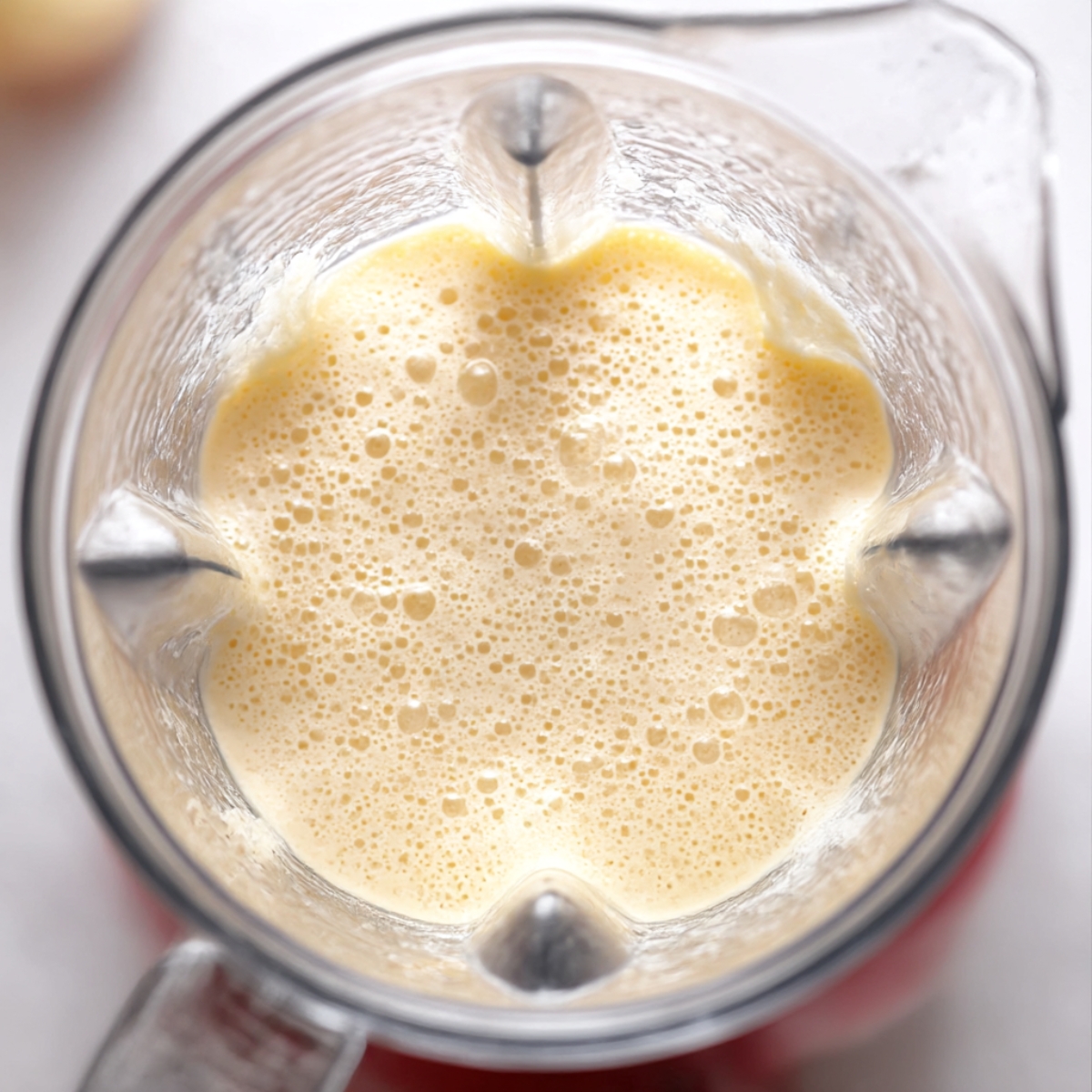 Top view of German pancakes batter blended until smooth and frothy inside a blender, preparing Dutch baby pancake recipe.