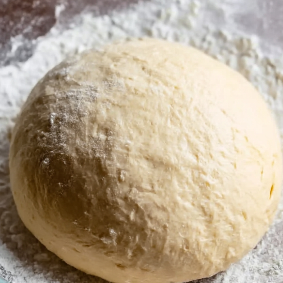 A close-up image of smooth, round dough resting on a floured surface, ready for the next step in making Dutch oven bread, showcasing its soft and well-formed texture.