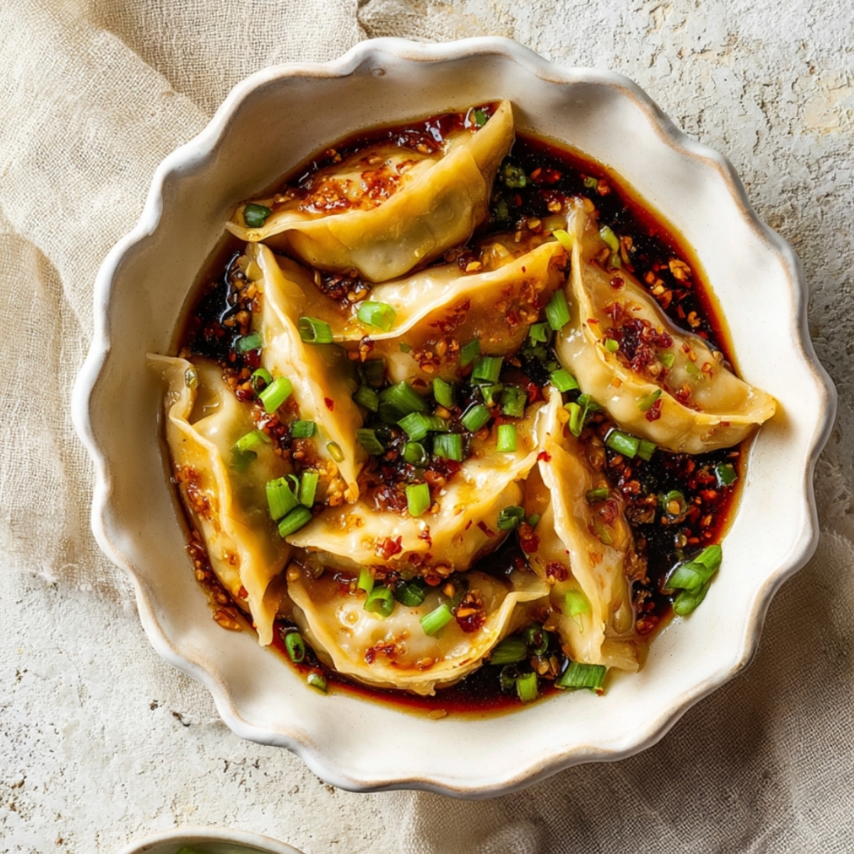 Potsticker soup served in a white bowl with tender dumplings in a savory chili oil broth, topped with green onions for an easy homemade dinner