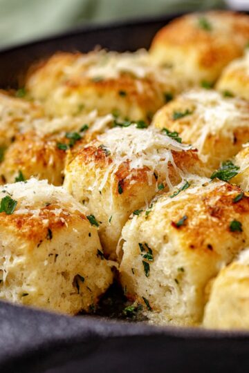 Golden, cheesy garlic parmesan bread bites baked to perfection, topped with melted parmesan cheese and fresh parsley, served in a skillet for an irresistible appetizer or side dish.