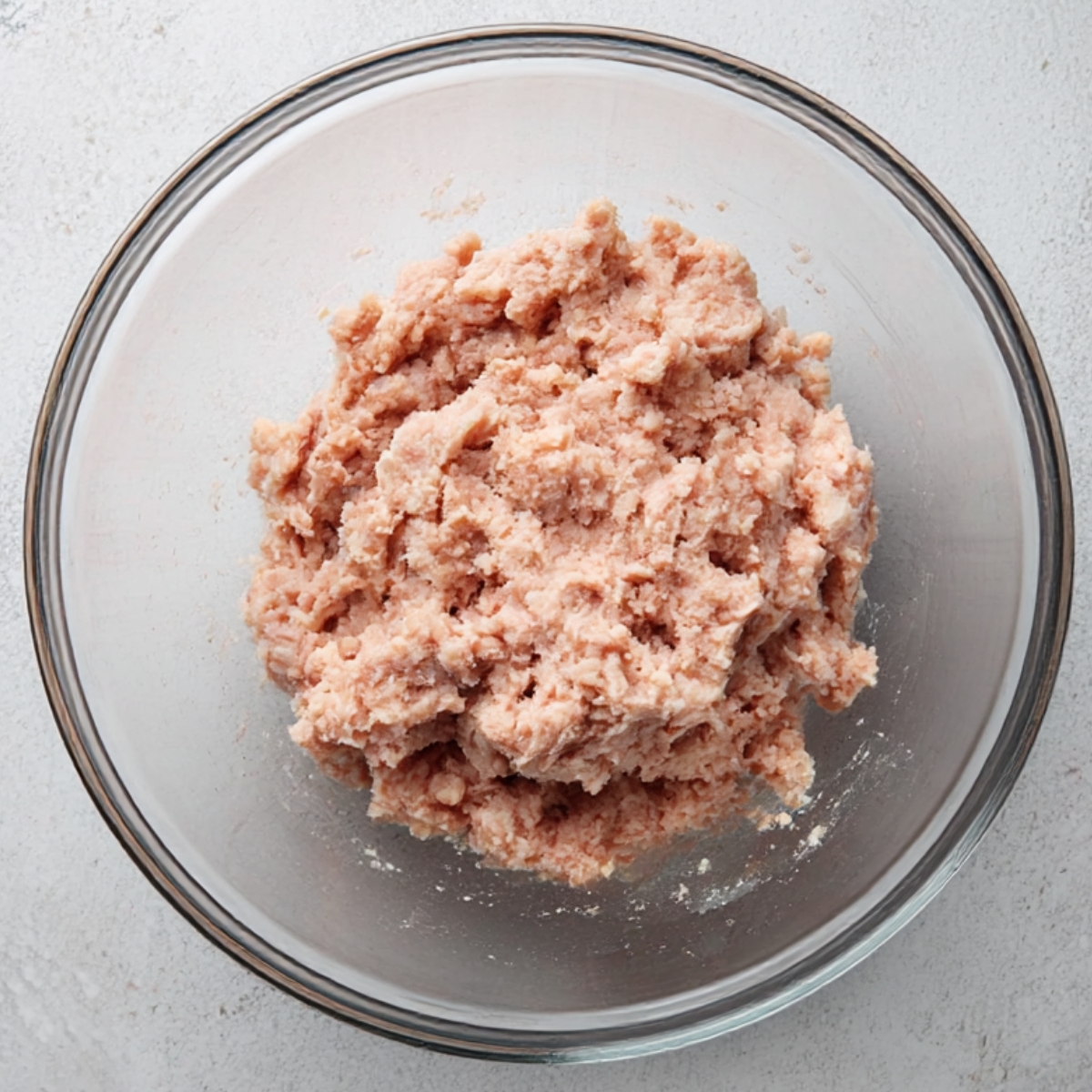 Glass bowl filled with raw ground turkey sausage, freshly prepared and ready to be shaped into patties or cooked