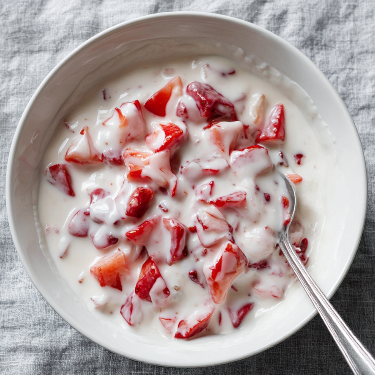 Fresh chopped strawberries mixed with creamy yogurt in a white bowl, ready to be dipped in chocolate or used for homemade chocolate-covered strawberry recipes. Healthy and easy dessert idea.