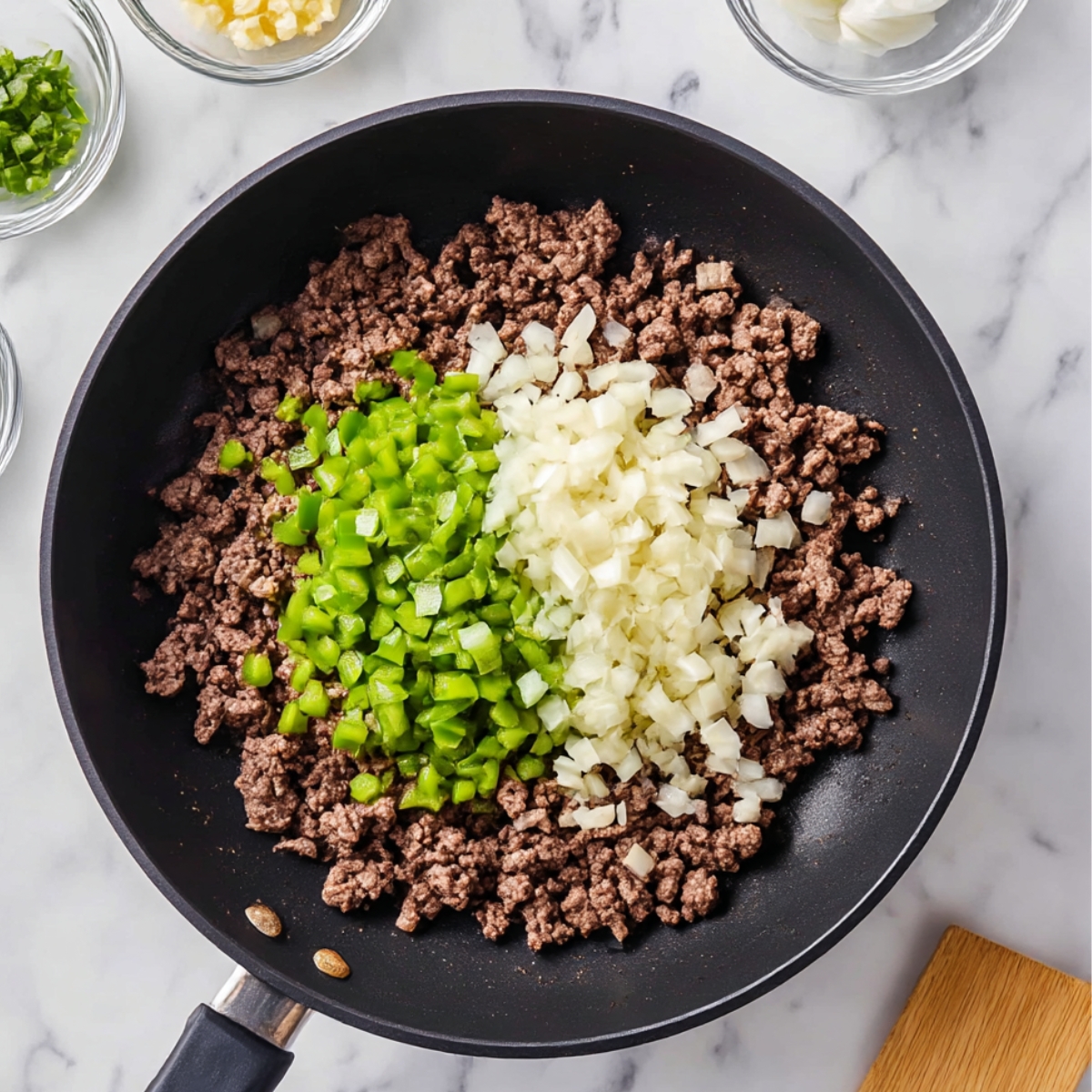 Ground beef cooking with chopped onions and green bell peppers for hobo casserole