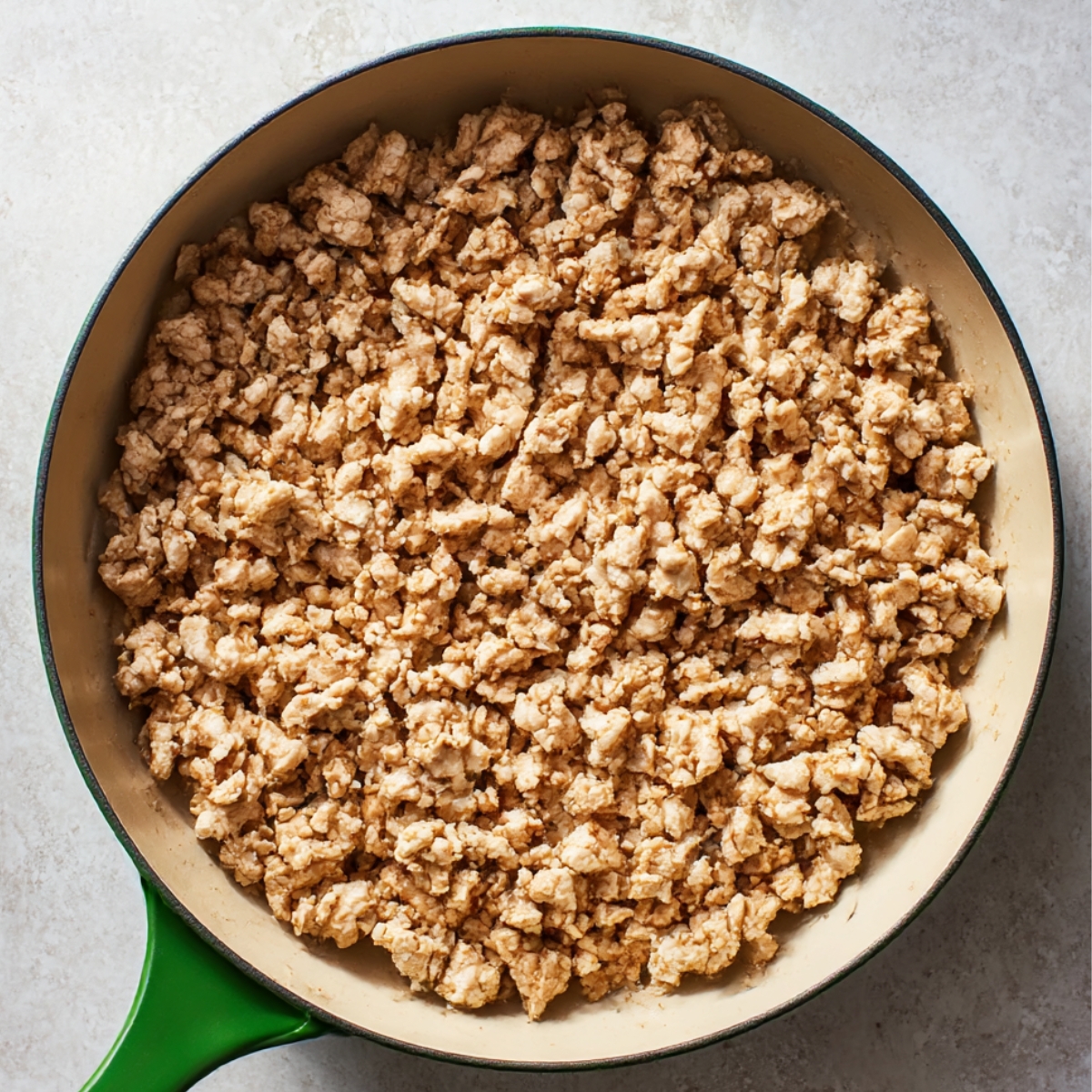 A skillet filled with cooked ground turkey, browned and crumbled, ready to be combined with shredded cabbage, carrots, and sauce for Egg Roll in a Bowl.