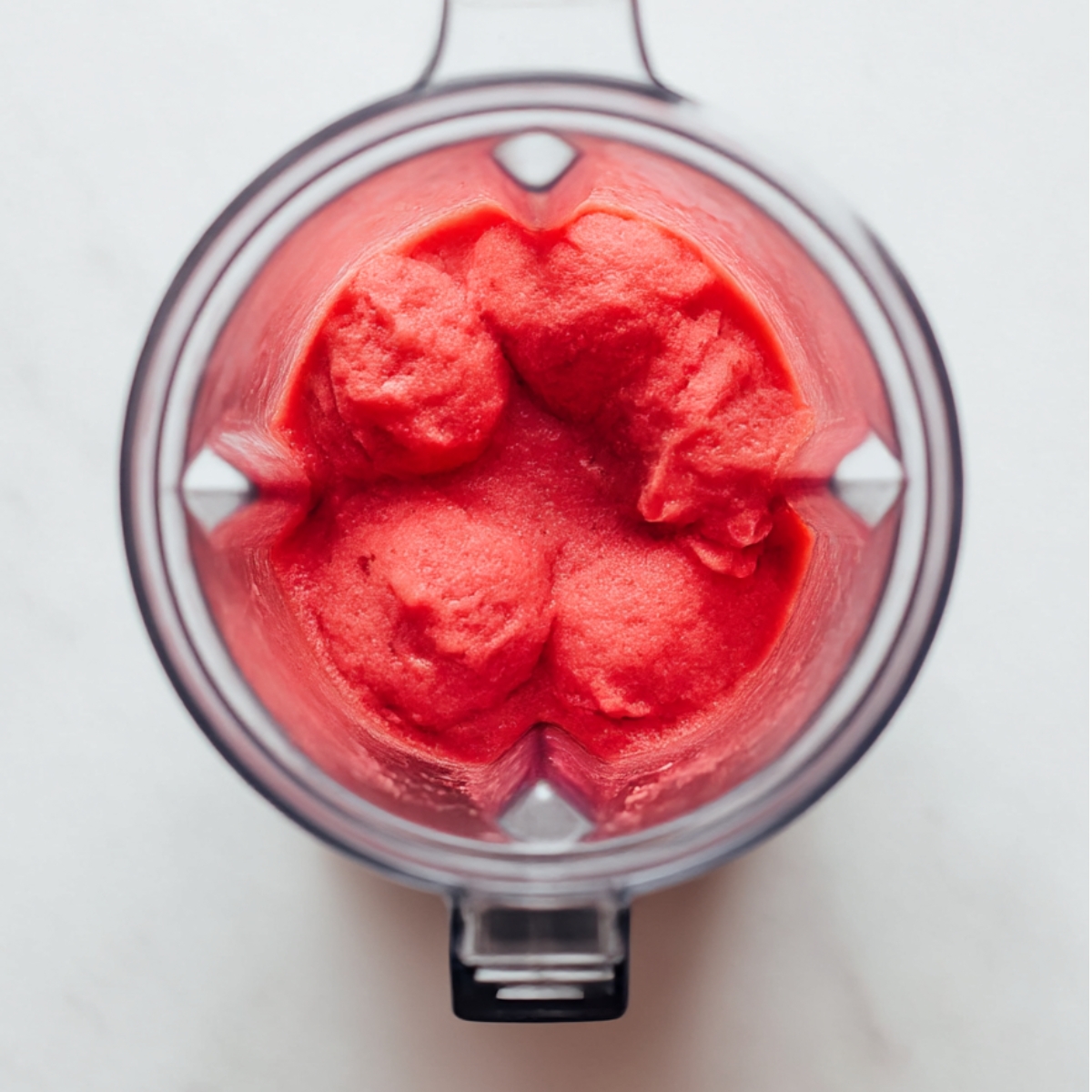 Top view of vibrant pink strawberry watermelon sorbet in a blender, smooth and creamy, perfect for a quick summer treat.