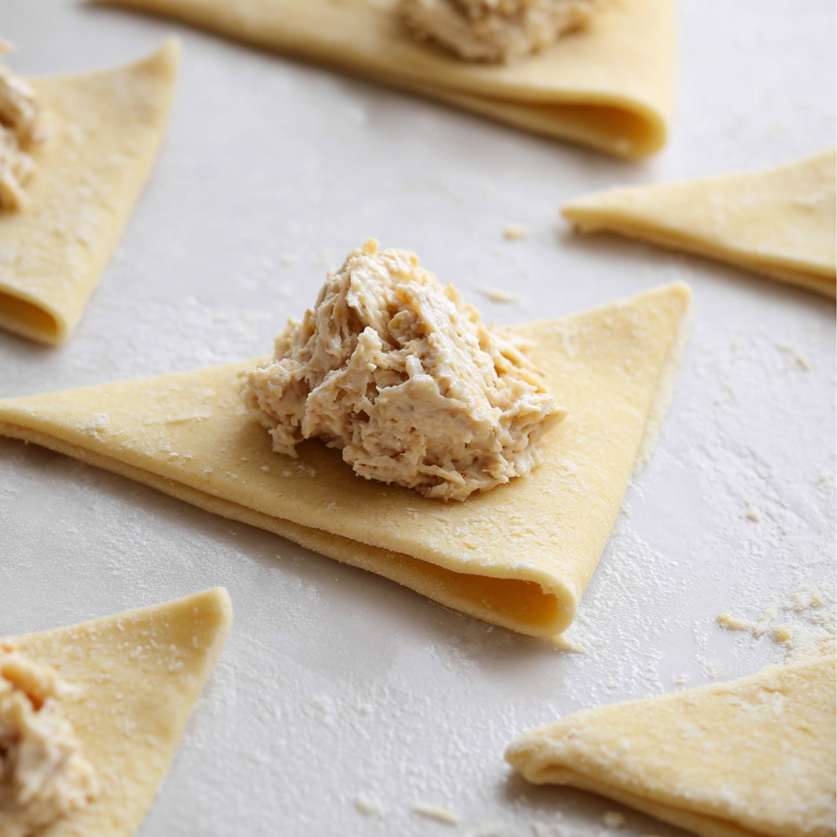 Bowl of shredded chicken mixed with creamy cheese and seasonings, ready to be used as filling for chicken crescents.