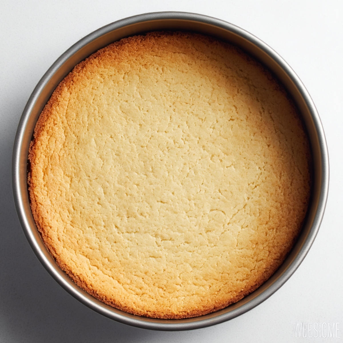 A perfectly baked keto cheesecake crust in a round pan, golden brown and firm, ready to be filled with creamy sugar-free cheesecake batter for a low-carb strawberry cheesecake.