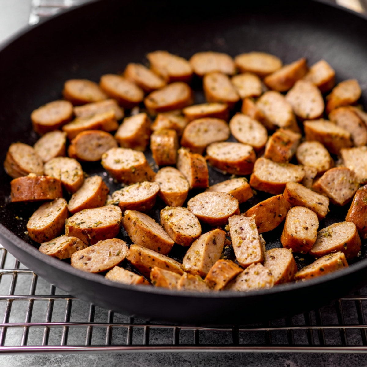Golden brown sliced breakfast sausage cooking in a skillet, perfect for adding savory flavor to a make ahead breakfast casserole.