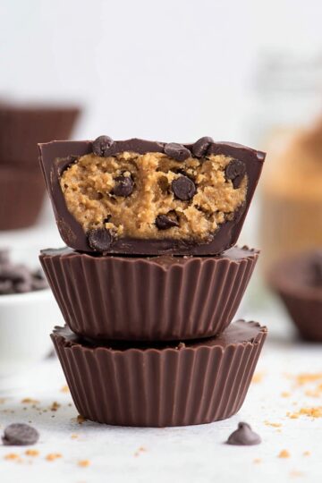 Stacked vegan chocolate cups filled with rich, gooey cookie dough and mini chocolate chips, perfect for a no-bake dessert or healthy treat.